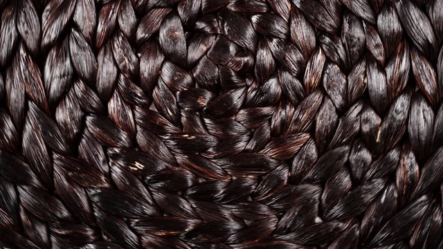 Dark brown wicker woven pattern rotating. Abstract background or texture. Top down view
