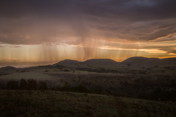 Rain falling on a distant mountain with orange sunset