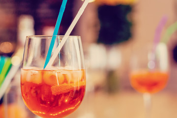 Glass of orange cocktail decorated at bar counter background.