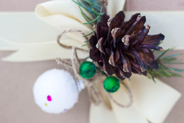 Gift box with ribbons decorations in the form of cones and branches of a Christmas tree close-up