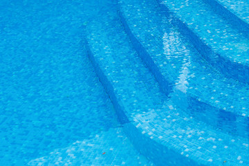 Curved steps at the resort swimming pool with mixed blue tile mosaic
