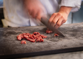Chef human hands cutting salami preparing food