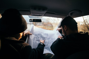 Two violent robbers sitting in a car looking at a blueprint of the building they want to rob while...