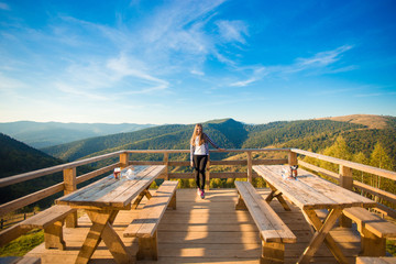 Young woman with long hair have rest in open air cafe on top of mountains and enjoy view