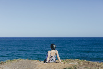 young girl  sitting on beach and looking at the sea