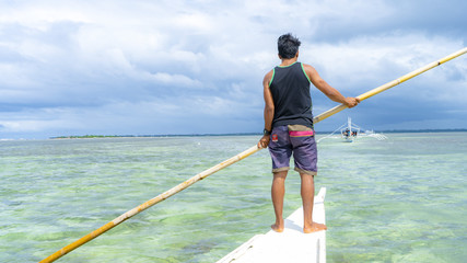 A standing man on a small boat for Island hoping tour with beautiful sea, bohol island, the philippines