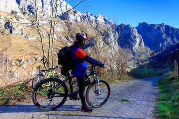 A cyclist with his mountain bike points his hand at the direction of the route