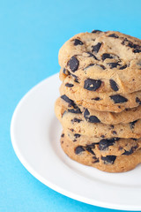 Stack of chocolate cookies on a plate. Chocolate chips cookies shot on blue background. Mock up for input text.