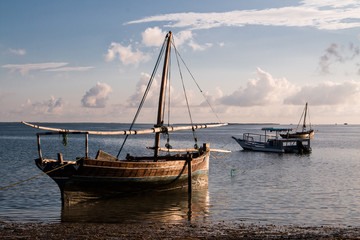 Closeup of a wooden sailboat on the water at the beach at sunrise in Mafia Island, Tanzania, with...