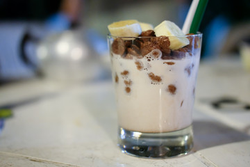 Banana, corn flakes chocolate in fresh milk in glasses