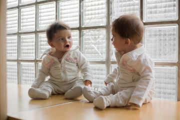 baby loking herself on the mirror