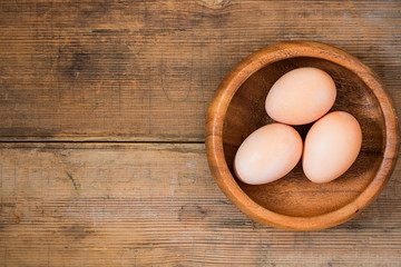 Easter eggs in wooden bowl on wooden background.