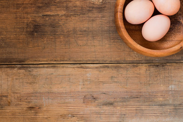 Easter eggs in wooden bowl on old wooden background.