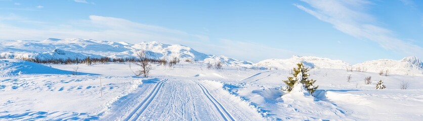 Obraz premium Wide panoramic view of snowy landscape with cross country ski track in Beitostolen. Winter in Norway