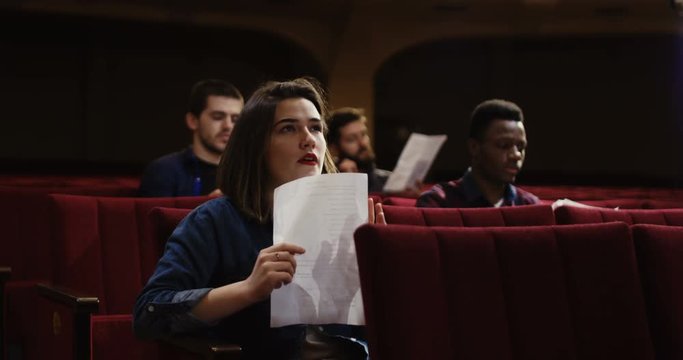 Medium shot of actors memorizing their lines while sitting in the auditorium