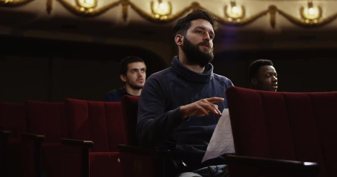 Medium shot of actors memorizing their lines while sitting in the auditorium