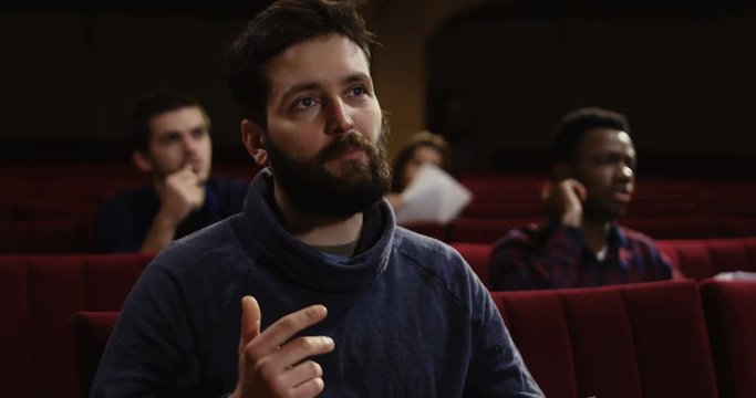 Medium shot of actors memorizing their lines while sitting in the auditorium