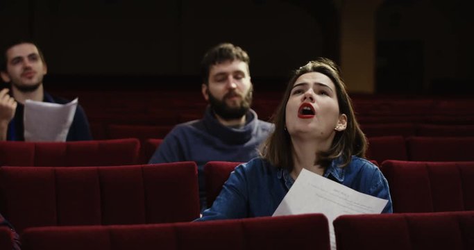 Medium shot of actors memorizing their lines while sitting in the auditorium