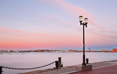 Boston Harbor after sunset. Photo shows Fan Pier Park brick sidewalk and Atlantic ocean . Boston Harbor is a natural harbor and estuary of Massachusetts Bay, located adjacent to city of Boston,MA.