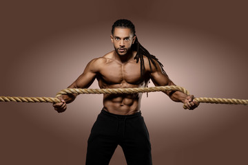 Muscular African American Black athletic fitness model wearing red underwear  holding a thick rope...