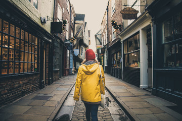 A rear view of a girl in a yellow coat walking along the historic street known as The Shambles in...