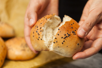 Bread in hands of woman. baker's hand breaking freshly baked sesame bun