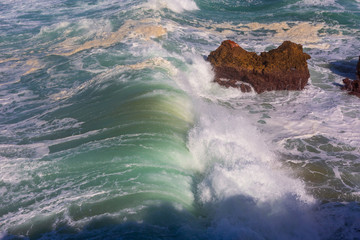 Sea waves hitting rocks cliff at Praia Da Bordeira, Portugal