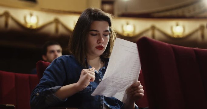 Medium shot of actors memorizing their lines while sitting in the auditorium