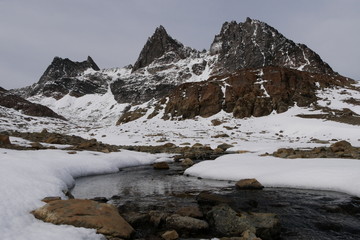Fototapeta na wymiar Sharp mountains with snow and a river on Dientes de Navarino Trek in Chile