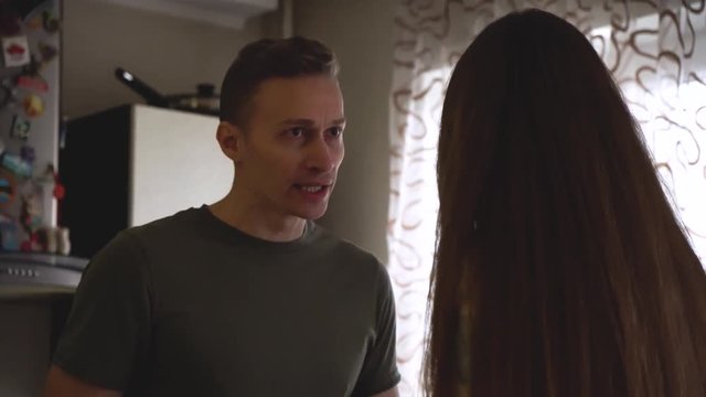 Upset young guy and his frustrated girlfriend having quarrel at home kitchen. Guy quarrels with his girlfriend in the kitchen