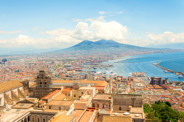 Aerial landscape view on town Naples. Port with ferrie, boats, colorful buildings and Vesuvio volcano with clouds on background. Neapoli hill photo, sunny day Italy, Campania. - obrazy, fototapety, plakaty