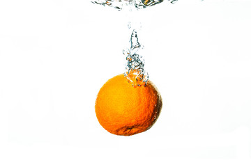 Fresh orange falls into water with white background