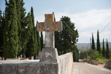 Old cross on a graveyard wall. Cross made out of stone