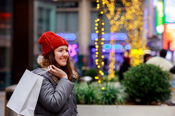Young girl at the street with shopping bags colorful lights bokeh