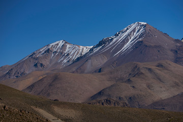 Fototapeta na wymiar Snow capped peaks and rugged landscape of the altiplano, around 4000 metres above sea level, in Lauca National Park, Chile. 