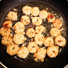 Cooking shrimps with butter in a black pan