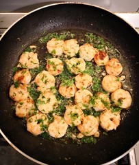 Cooking shrimps with butter in a black pan