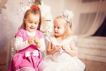 Happy little sisters wearing Christmas opening gift boxes living room on Christmas eve. Celebrating Xmas at home.