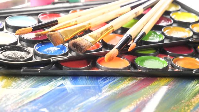 Paint brushes and watercolor paints in motion on the table