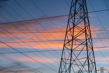 electricity pylon tower against blue and orangesky