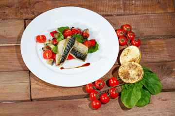 Mackerel baked with lemon, cherry tomatoes, vegetables and spices.