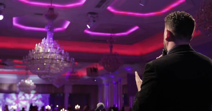 Singer man on stage, back view, concert hall background. The vocalist sings a song