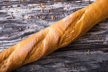 Bread baguette lying on a wooden table diagonally