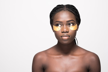 Close-up of a young african woman with patches under eyes from wrinkles and dark circles isolated on white background