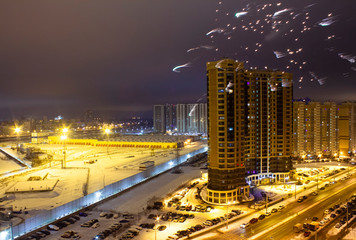 Fototapeta na wymiar Sparks of New Year's fireworks in a new residential area next to high-rise buildings on the outskirts of the city of St. Petersburg on New Year's Eve.