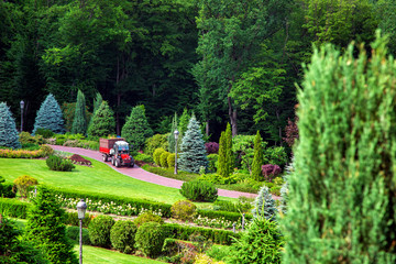 The landscape design of the backyard of the mansion with clipped bushes and hedges, green grass and...