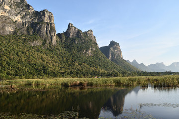 Rock cliff and green forest on limestone mountain on the vast wetland at Khao Sam Roi Yot National Park , Thailand 