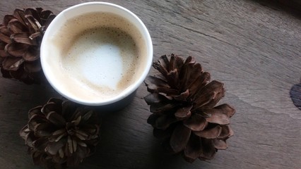 Coffee in a glass of paper placed on a wooden table with dry flowers placed beside