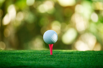 Golf ball on tee in beautiful golf course at bokeh background. Golf ball on green in golf course