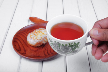 Man holding a cup of tea and sweet donut on wooden plate over  wooden tabletop with wooden  spoon. Celebration concept